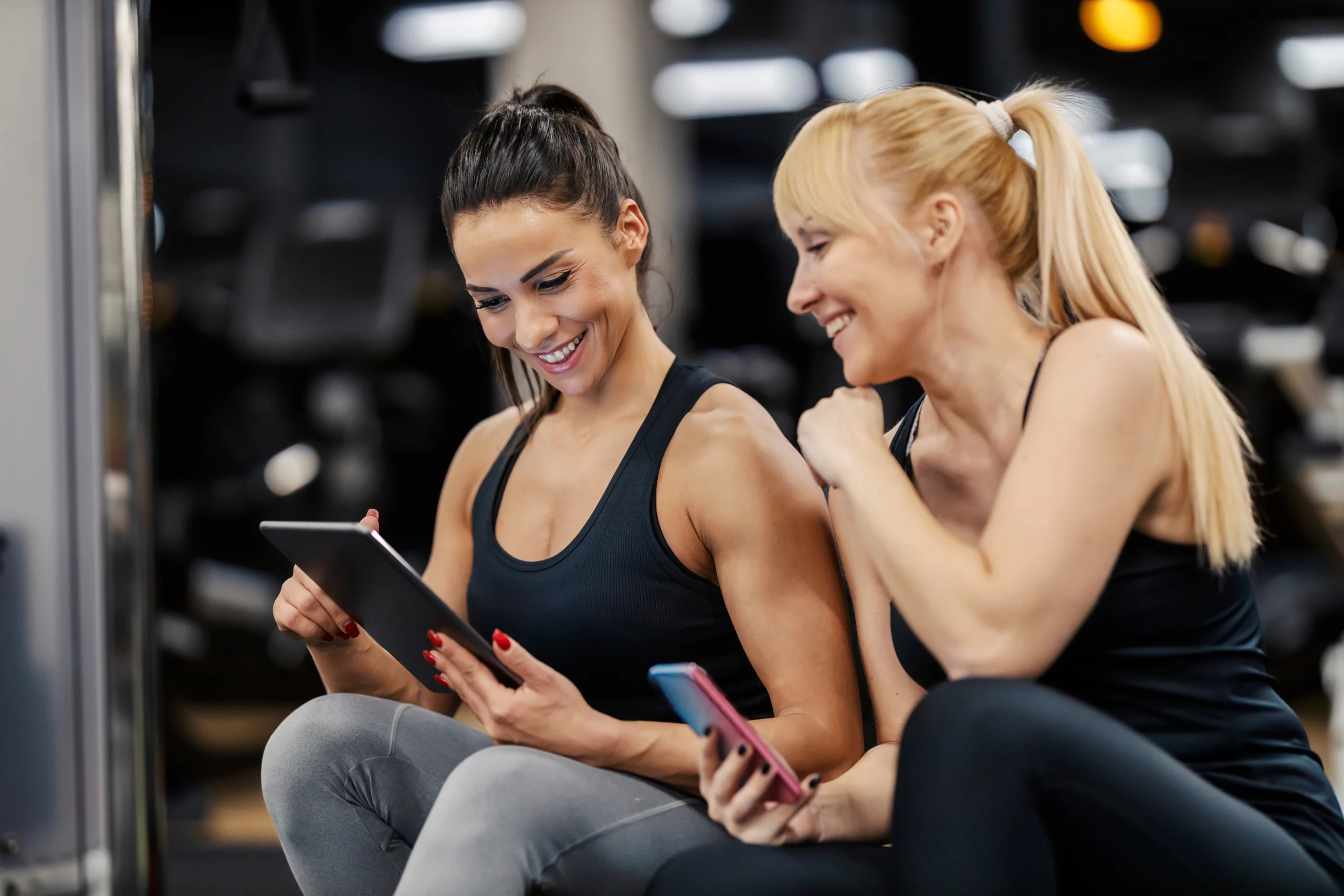personal trainer and client look at phone; direct debit for personal trainers | Biz Core