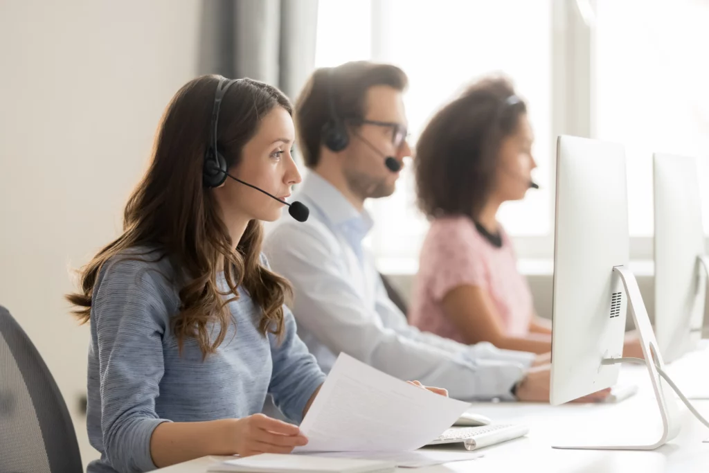 Three people wearing headsets in an IT help desk