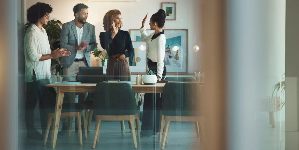 A group of people high five in a meeting room