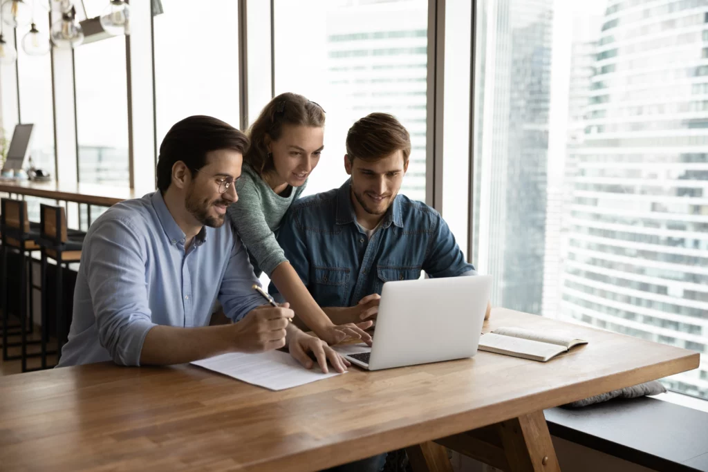Three people looking at a laptop in their office